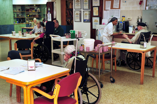 Nursing home patients in wheelchairs around tables