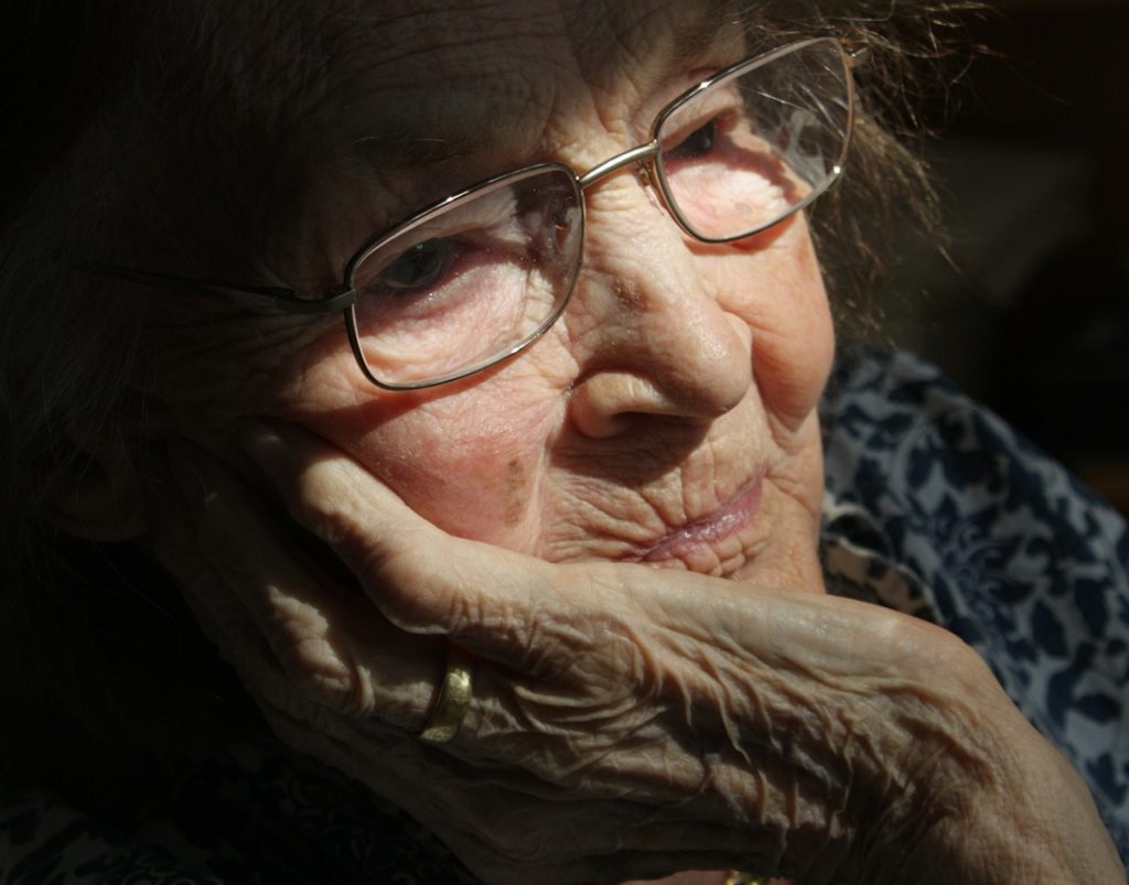 Elderly woman with her hand against her face