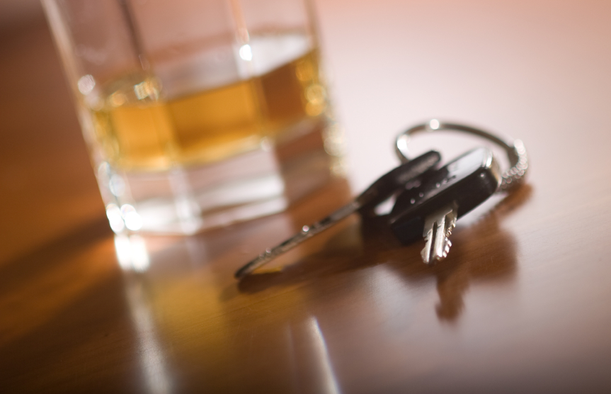 A glass of brown liquor next to car keys