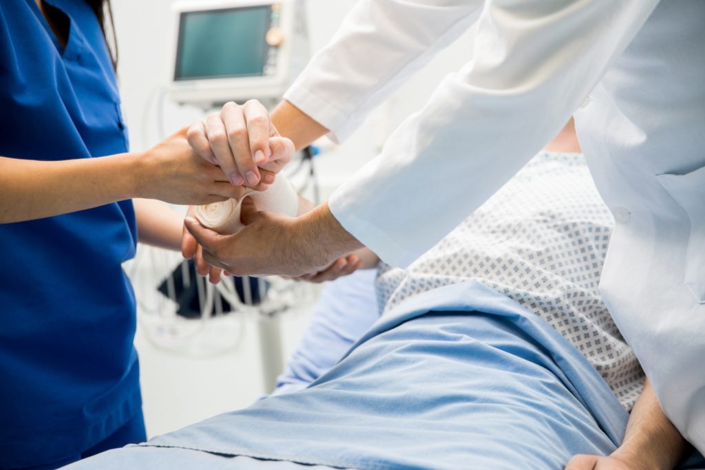 Doctors and Nurses holding hands over a patient