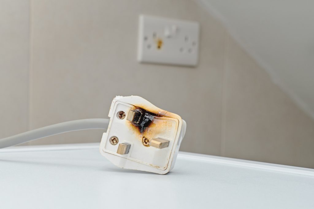 A burnt extension cord sitting on a white table.