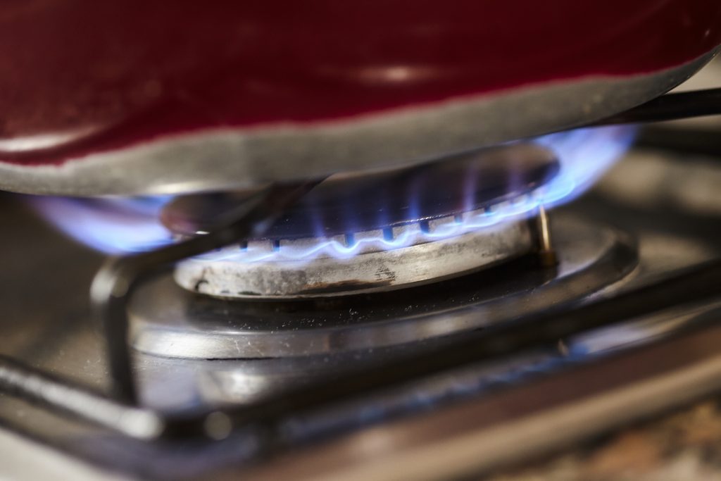 Detail of a gas stove lit with a blue flame