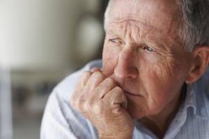 Elderly man pondering with his hand rested against his face.