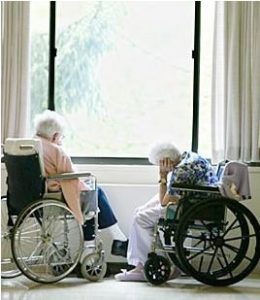 two elderly people next to a window in wheelchairs. 