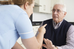 Woman yelling at an old man who has his hand lifted slightly to gesture for her to calm down. 