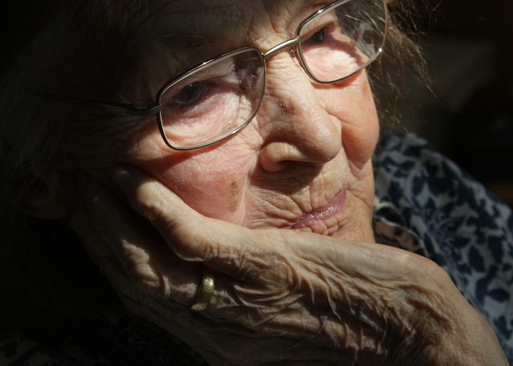 Elderly woman holding her face in distress