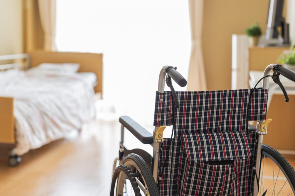 Wheelchair next to bed in a clean wood room