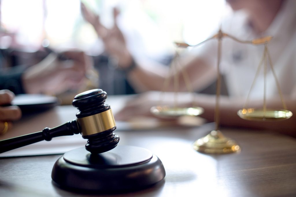 Lawyer and client having a meeting with a gavel and scales in the foreground