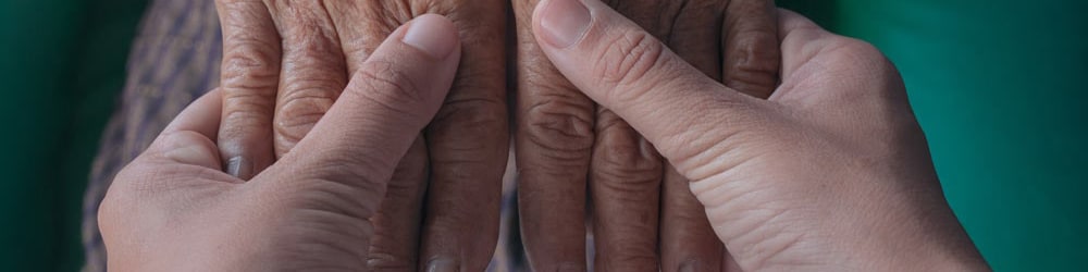 Person holding an elderly person's hands