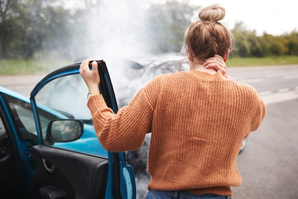 Woman standing by the door of a crashed car