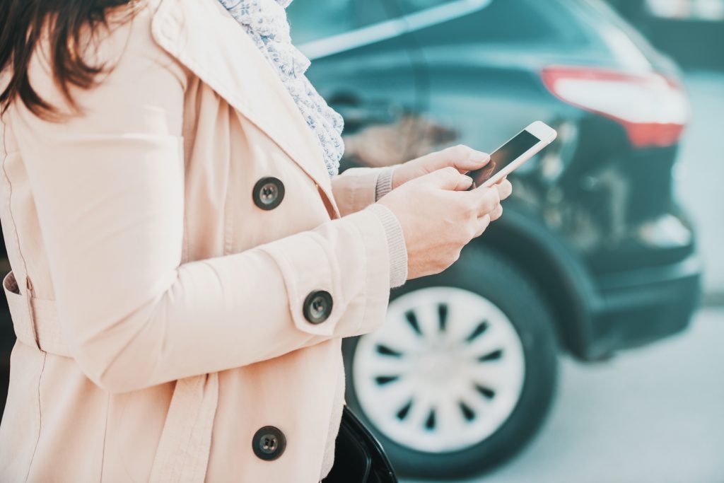 Woman with a phone next to a car