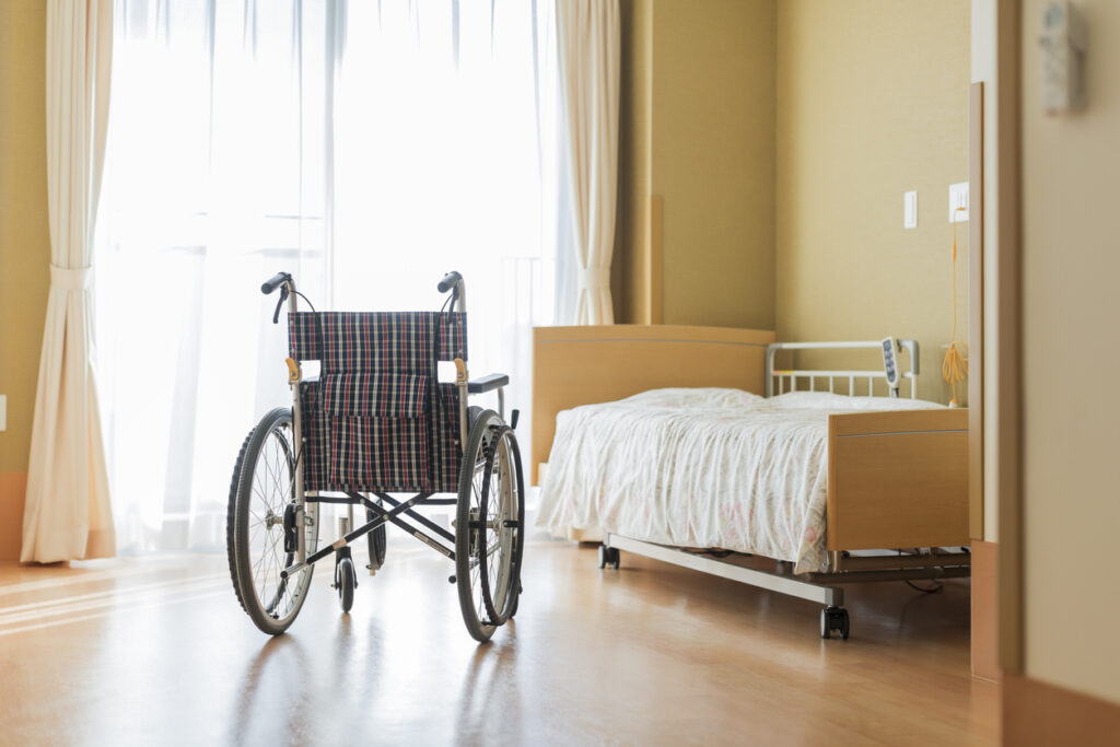 A wheelchair and bed in a nursing home bedroom