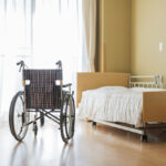 A wheelchair and bed in a nursing home bedroom