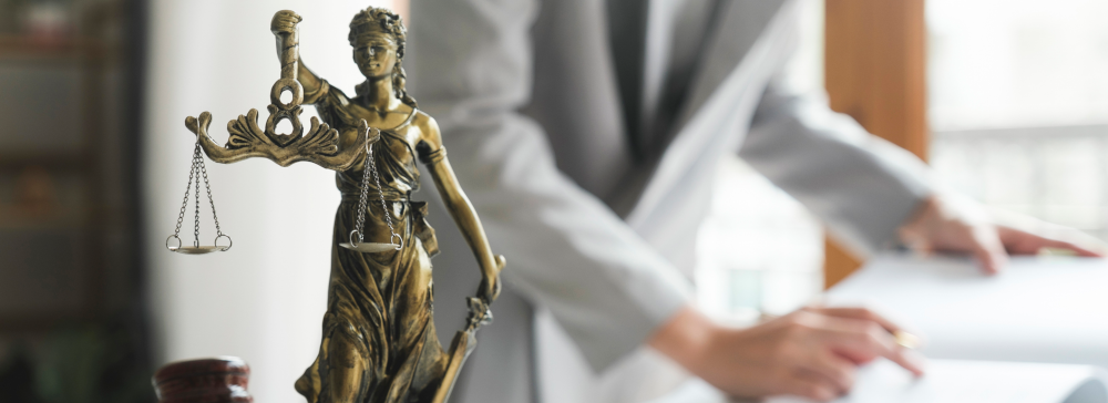 Lady Justice with Dallas sexual abuse lawyer behind her looking at a book. 